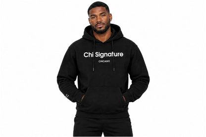 “Black male model wearing a black Chi Signature Chicago hoodie with white chest lettering, hands in the front pouch pocket.”